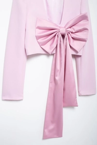 Détail de la veste courte rose avec un grand nœud en satin et de longs rubans en soie