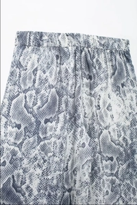 Detailed view of women's wide-leg trousers featuring a grey snake print and elastic waistband