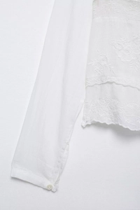 Détail de la broderie florale blanche et du poignet boutonné sur un chemisier lin