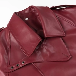 Détail de la veste en similicuir bordeaux avec œillets métalliques et coutures d'épaule