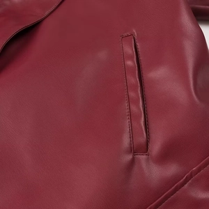 Gros plan sur la texture du similicuir bordeaux et les détails de couture de la poche