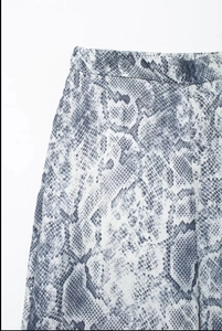 Detailed close-up of grey and white snake print trousers with premium waistband stitching
