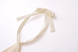 Close-up of knit fabric texture with cream woven halter tie and bow detail