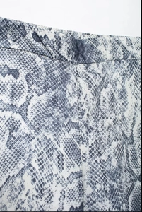 Close-up of elastic waistband on snakeskin pattern wide-leg pants with detailed stitching