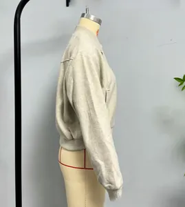 Detail view of the ribbed cuffs and hem of a soft knitted bomber jacket in beige