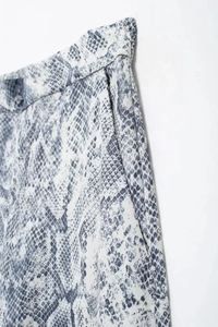 Detail of snake print trousers featuring side pockets and high-quality woven fabric texture