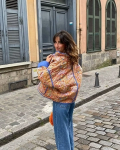 Detailed view of quilted floral jacket with blue piping against a street backdrop