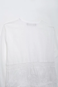 Détail du haut blanc à manches longues avec empiècement en dentelle et broderie florale