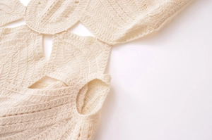 Close-up detail of cream crochet knit dress featuring leaf-shaped openwork patterns
