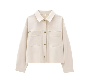 Detail of creamy white shacket with golden metal buttons and textured fabric pockets