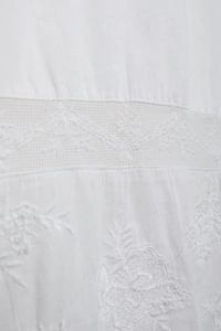 Détail de chemise en coton blanc avec broderie florale et coutures en dentelle