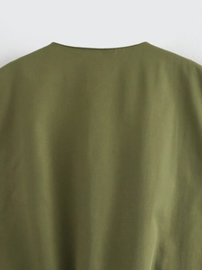 Detail of olive green V-neck vest showing smooth woven fabric and neat neckline stitching