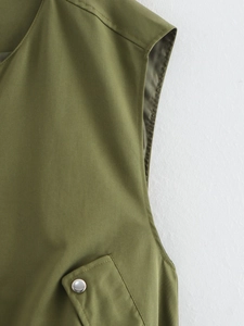 Detailed close-up of olive green vest fabric with silver metal snap buttons and fine stitching