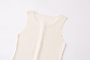 Détail du gilet en maille crème avec texture verticale et boutons dorés élégants