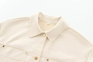 Close-up of apricot suede jacket with gold metal buttons and front flap pockets detail