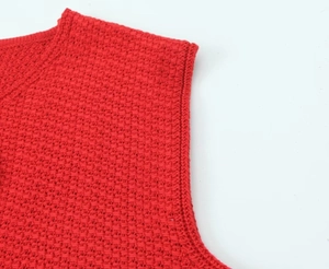 Gros plan sur le gilet en tricot rouge montrant la maille nid d'abeille et le col fini