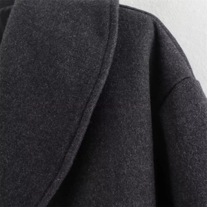 Macro detail of charcoal grey wool-like fabric texture on the collar of a stylish coat