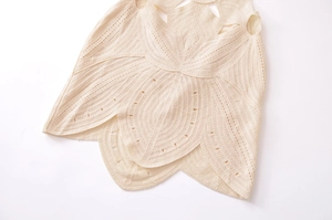 Detailed close-up of intricate 3D crochet floral patterns on a white knit vacation dress