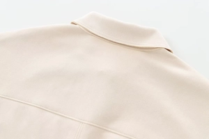 Detailed macro view of beige faux suede fabric with precise double stitching on the collar
