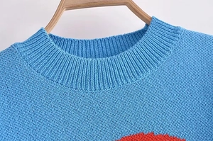 Detailed close-up of blue knit sweater crew neck with ribbed texture on wooden hanger