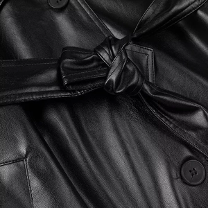 Detail of black faux leather trench coat featuring a waist belt tie and matte buttons