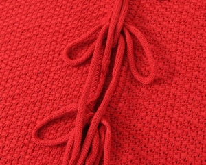 Détail du gilet en maille rouge montrant la texture et le cordon de serrage tissé