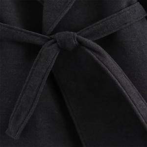 Detailed view of the black wool coat waist with a matching tied belt and soft texture