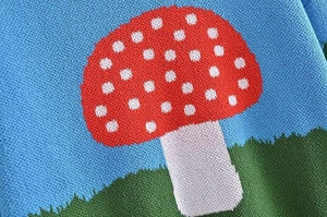 Detailed close-up of cartoon mushroom jacquard knitting on blue and green sweater fabric