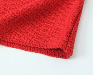 Gros plan sur le gilet en maille rouge montrant la texture épaisse et les coutures