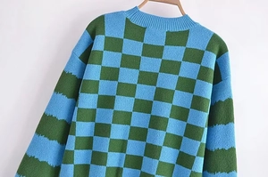Detail of the ribbed round neckline and blue-green checkerboard knit pattern on a sweater