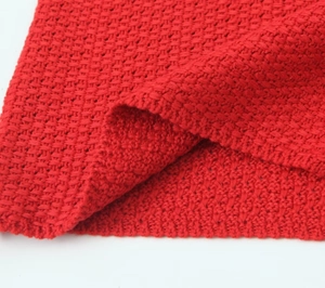 Détail de la veste en tricot rouge montrant la texture épaisse et le tissu éclatant