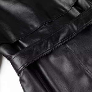 Macro view of black leather jacket texture showing premium stitching and belt detail