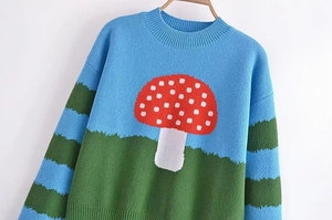 Detail of sky blue knit sweater featuring mushroom pattern and ribbed texture cuffs