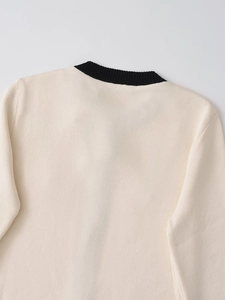 Detail of the knit sweater featuring a black ribbed neckline on cream fabric