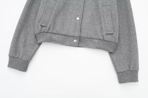 Close-up of grey wool bomber jacket showing silver buttons and ribbed knit hem details