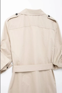 Détail d'une robe trench beige clair avec épaulettes et ceinture assortie à la taille