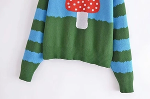 Detail of colorful mushroom knit sweater with blue and green striped sleeves and ribbed cuffs