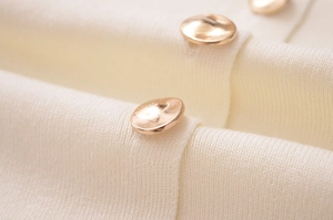 Gros plan détaillé sur la maille blanc cassé et les élégants boutons dorés polis
