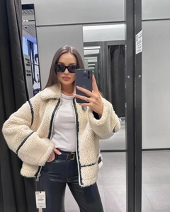 Dettaglio della giacca in shearling sintetico con bordi in pelle nera e cerniera