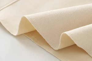 Detail shot of beige faux suede fabric texture with high-quality double stitching