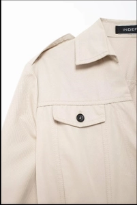 Détail de robe chemise beige montrant les épaulettes et le revers avec bouton noir chic