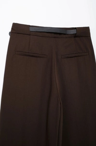 Vue détaillée du pantalon marron foncé avec taille en cuir noir et poches passepoilées