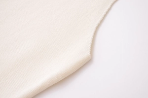Gros plan détaillé du tissu en maille crème montrant la texture fine et les coutures de qualité
