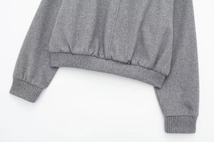 Detail of ribbed hem and cuffs on a grey loose pilot jacket with textured knit fabric