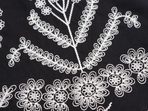 Nahaufnahme weißer Stickereidetails auf schwarzer ärmelloser Vintage-Weste für Damen