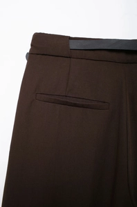 Détail d'un pantalon marron avec ceinture noire et poche passepoilée à l'arrière