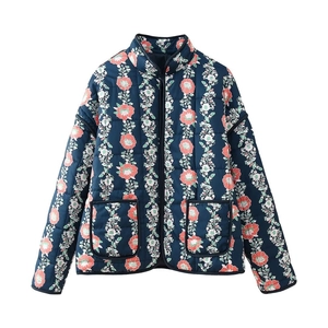 Detail of navy quilted jacket featuring pink floral patterns and black piped pockets