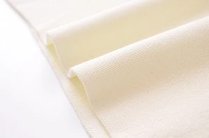 Gros plan sur la texture du tricot fin de couleur crème avec détails de couture précis
