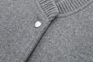 Detailed view of grey bomber jacket with ribbed knit collar and silver metal button