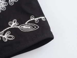 Detailaufnahme einer schwarzen Weste mit weißer Blumenstickerei im Vintage-Stil und Handwerk